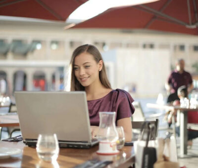 donna-in-camicia-viola-seduta-a-tavola-utilizzando-macbook
